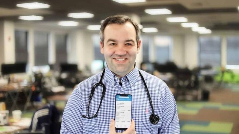 Nurse Chris Caulfield holding up phone with app displayed