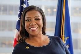 New York Attorney General Letitia James smiles in front of U.S. and state flags.