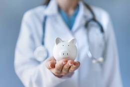 Doctor holding small piggy bank