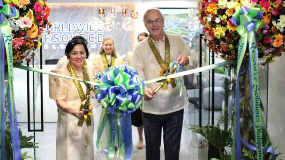 Leaders in traditional Filipino attire cut a ceremonial ribbon surrounded by large floral arrangements at the launch event for a virtual nursing hub in Quezon City, Philippines.
