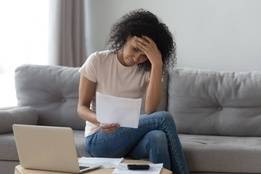 Stressed woman doing finances on laptop at home