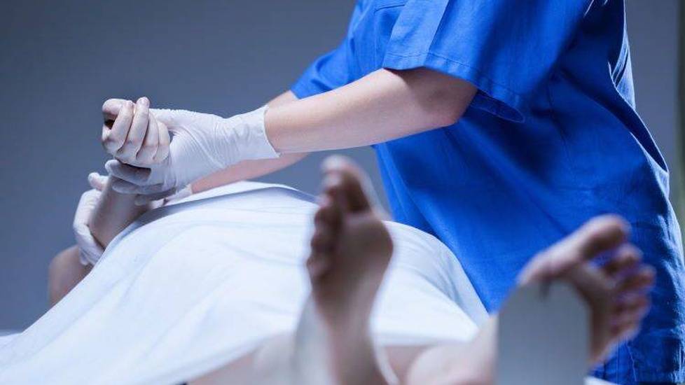 Nurse checking on deceased patient in morgue