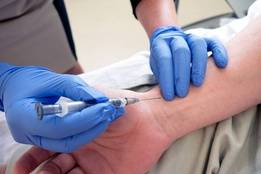 Nurse with gloves administering shot to patient's wrist