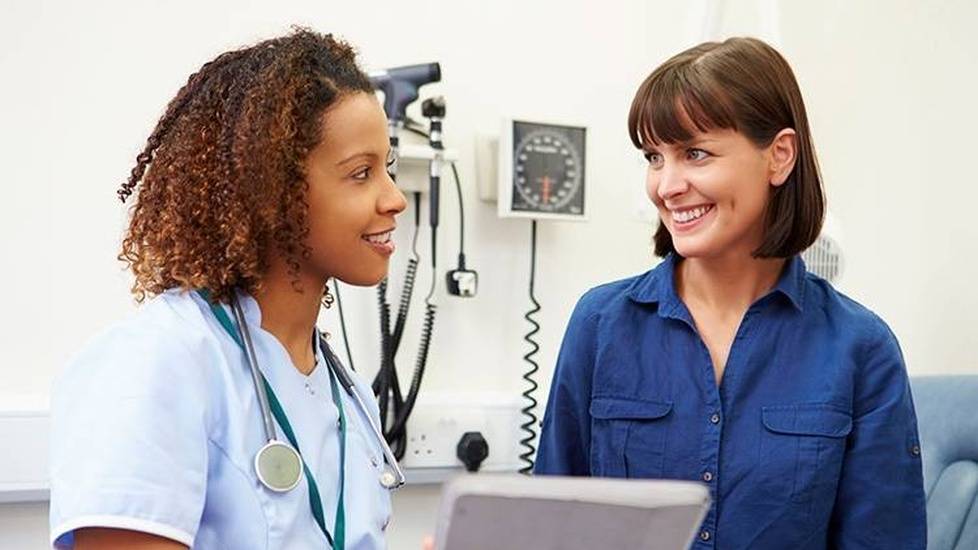 Nurse with chart happily discussing with patient in hospital room