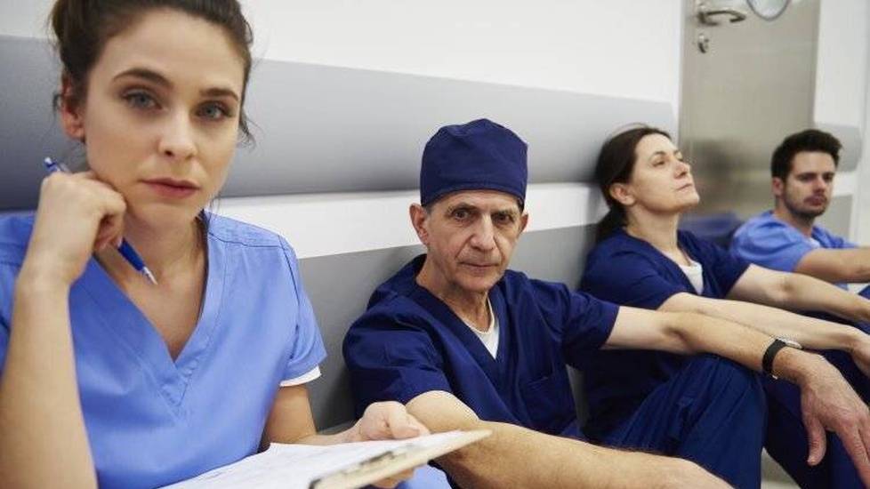 Group of tired and stressed healthcare workers in hospital hallway
