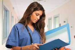Young nurse looking at folder in hospital hallway