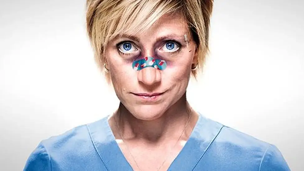 Edie Falco as Nurse Jackie, in scrubs with bandages on her nose, staring intensely ahead.