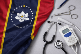 Mississippi state flag displayed beside a stethoscope and fetal Doppler, representing nurse-midwifery and maternal health care.