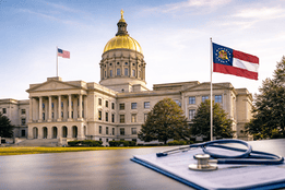 Georgia State Capitol with gold dome and Georgia state flag, with a medical clipboard and stethoscope in the foreground.