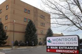 Exterior of Montrose Regional Health hospital in Colorado with a sign pointing to the main entrance and emergency department.