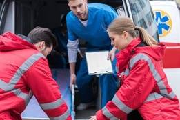 Two EMTs and a nurse moving patient into ambulance
