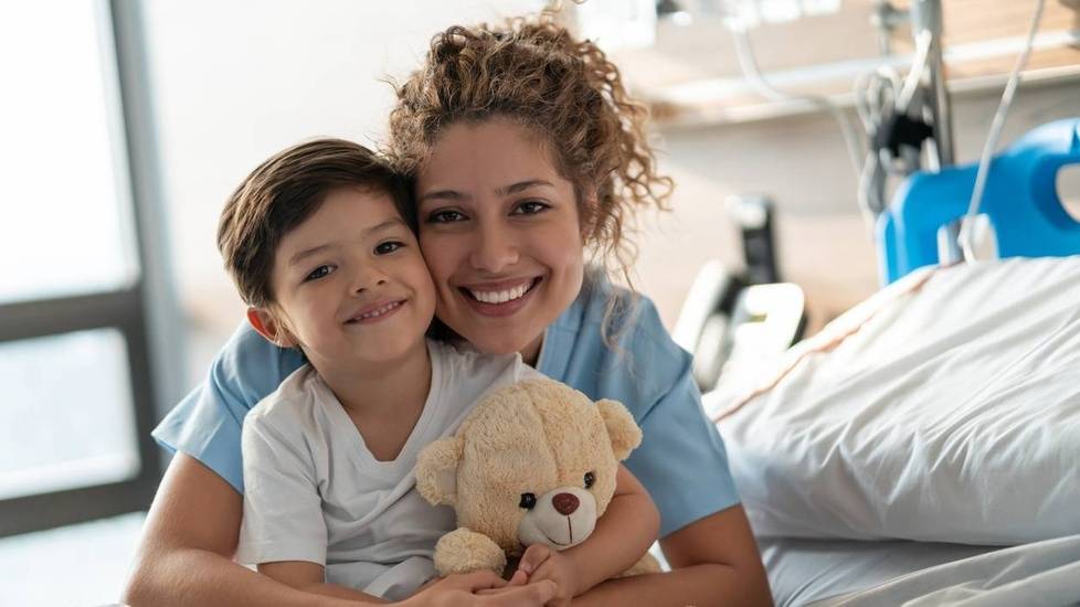 Nurse holding child patient in hospital bed