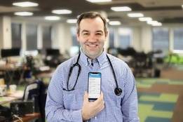 Nurse Chris Caulfield holding up phone with app displayed