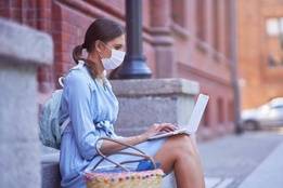 Female college student with mask on studying outside