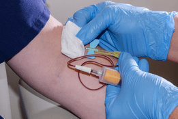 Nurse with gloves drawing blood from patient's arm