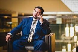 Lawyer talking on phone while sitting in chair in a lobby