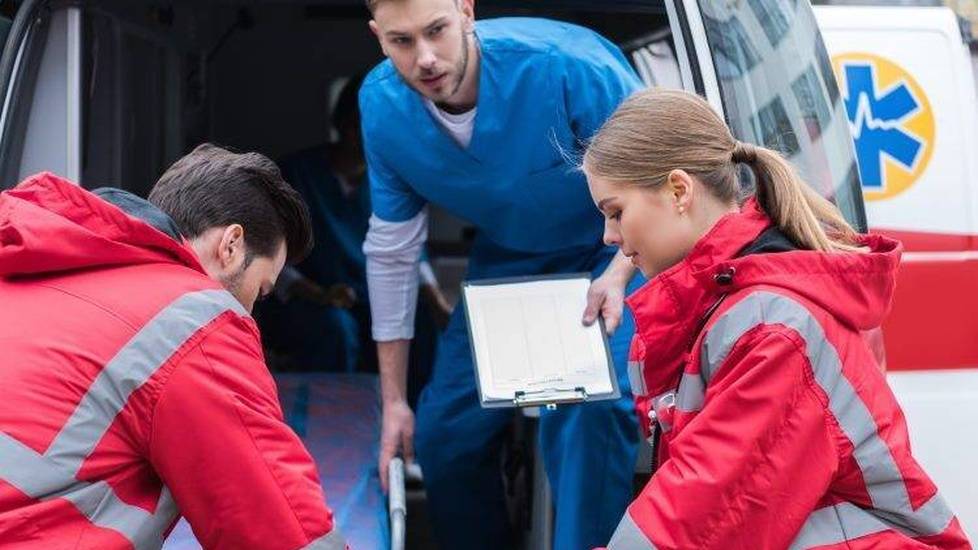 Two EMTs and a nurse moving patient into ambulance