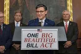A group of lawmakers stands behind a podium displaying a sign that reads "ONE BIG BEAUTIFUL BILL ACT" with an American flag graphic at the top.