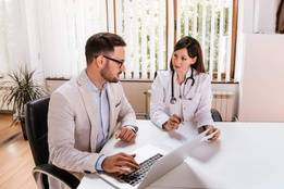 Businessman sitting at desk with doctor