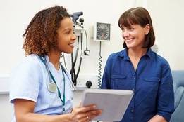 Nurse with chart happily discussing with patient in hospital room
