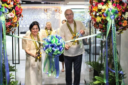 Leaders in traditional Filipino attire cut a ceremonial ribbon surrounded by large floral arrangements at the launch event for a virtual nursing hub in Quezon City, Philippines.
