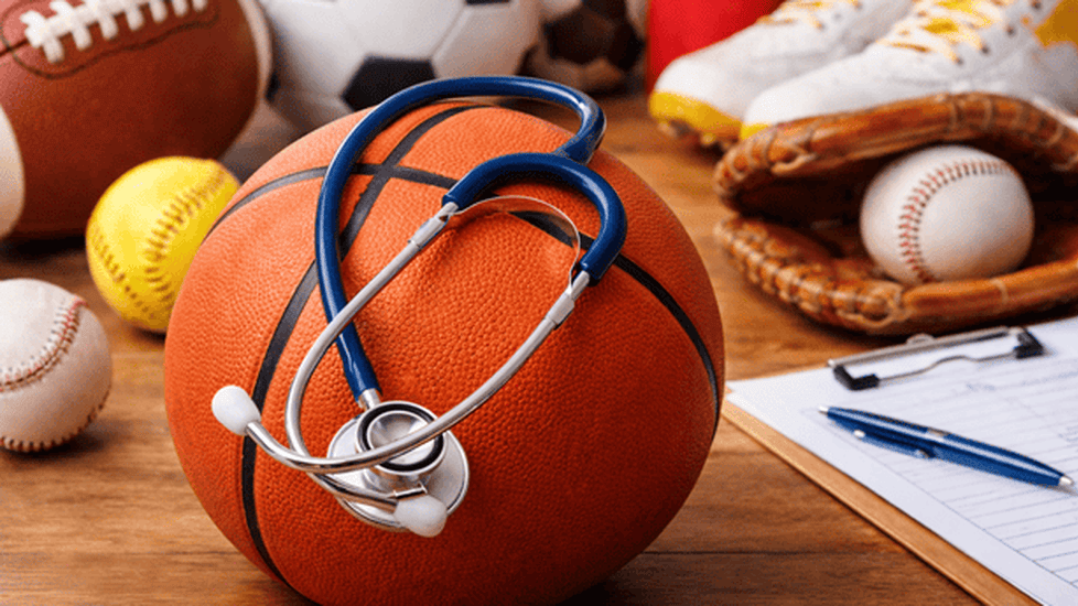 School sports equipment with a stethoscope placed on a basketball, symbolizing healthcare providers approving K-12 athletic physicals.