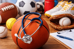 School sports equipment with a stethoscope placed on a basketball, symbolizing healthcare providers approving K-12 athletic physicals.