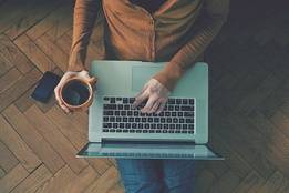 Person holding coffee and working on laptop computer