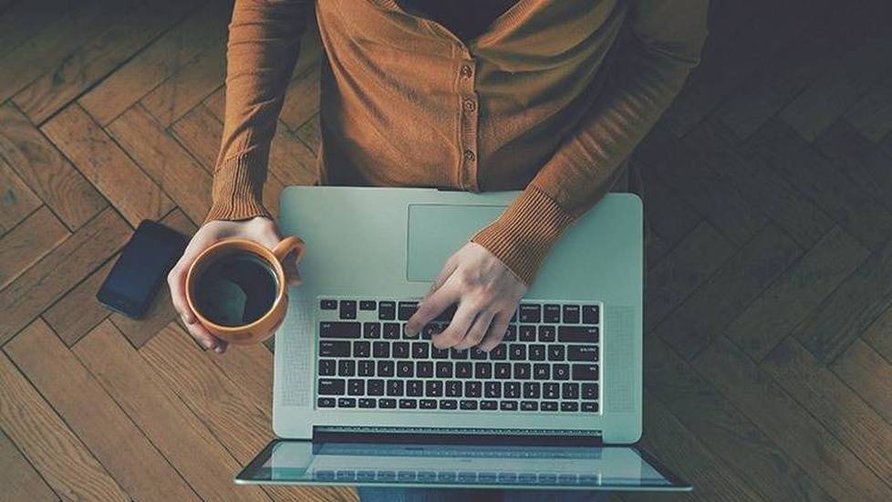 Person holding coffee and working on laptop computer