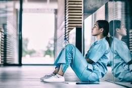 Distressed nurse sitting in empty hospital hallway